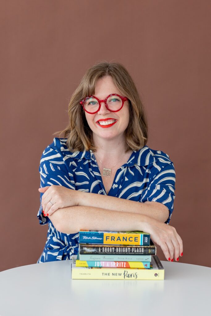 Author leaning on a stack of books